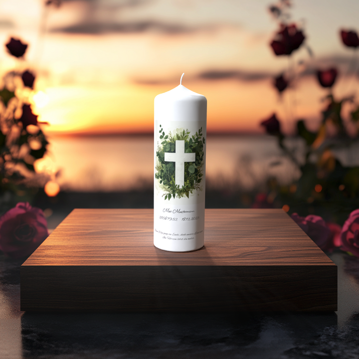 Weiße Trauerkerze mit Kreuz im Eukalyptuskranz – Symbol für Hoffnung, Frieden und Erinnerung, im Sonnenuntergangslicht aufgenommen.