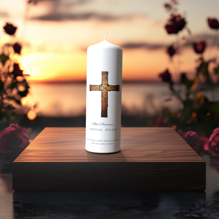 Weiße Trauerkerze mit gebrochenem Kreuz in Kupferoptik auf Holzpodest vor Sonnenuntergang, Symbol für Trauer, Trost und neues Licht.