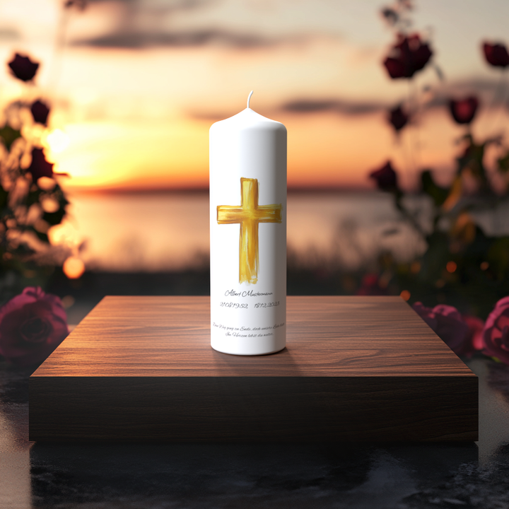 Weiße Trauerkerze mit goldenem, handgemaltem Pinselkreuz auf Holzpodest bei Sonnenuntergang – Symbol für Licht, Würde und Erinnerung.