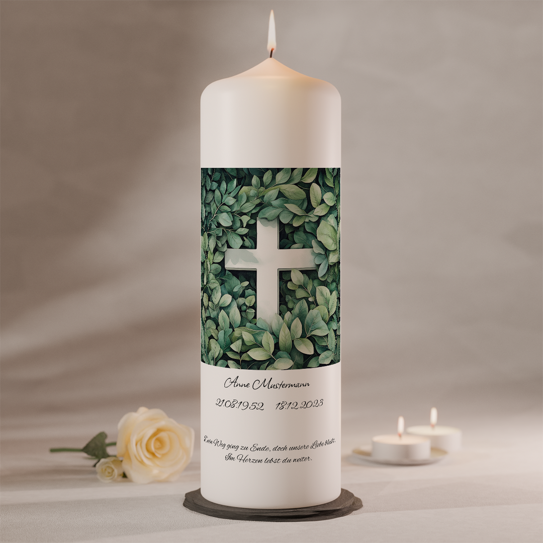 Trauerkerze mit weißem Kreuz im grünen Blättermotiv auf moderner Gedenkkerze