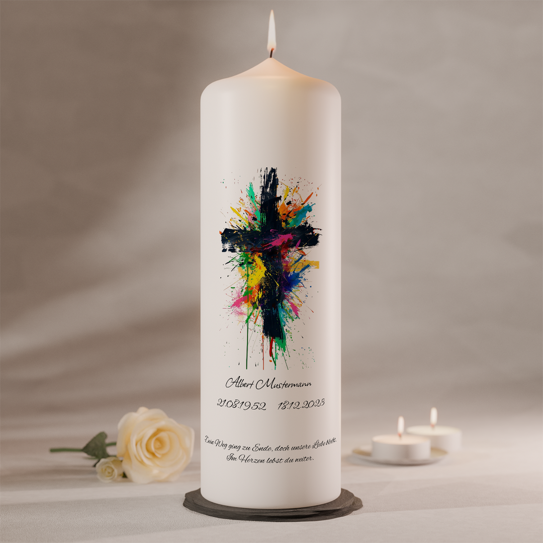 Moderne Trauerkerze mit schwarzem Kreuz und farbigen Pinselstrichen auf weißer Gedenkkerze