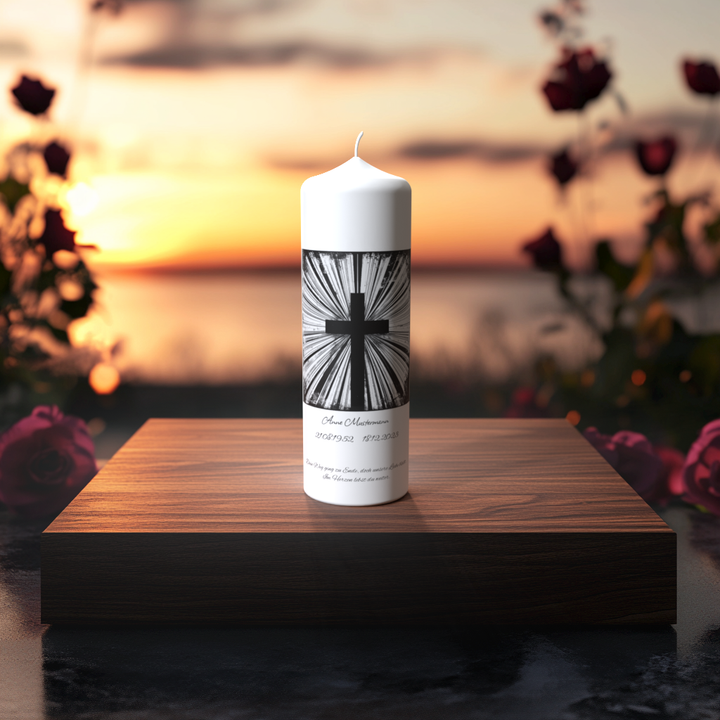 Weiße Trauerkerze mit schwarzem Strahlenkreuz auf Holzpodest bei Sonnenuntergang – Symbol für Licht, Trost und Erinnerung.