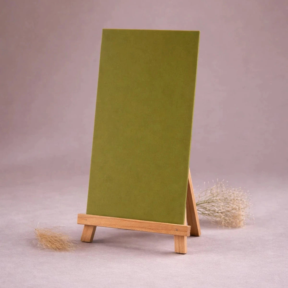 ambragrüne wachsplatte zur kerzengestaltung auf kleiner holzstaffelei vor neutralem beigem hintergrund