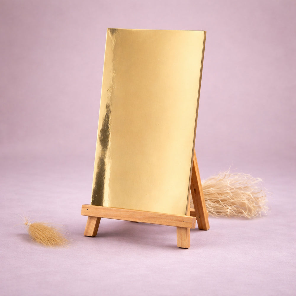 goldene wachsplatte zur kerzenverzierung auf kleiner holzstaffelei vor hellem neutralem hintergrund