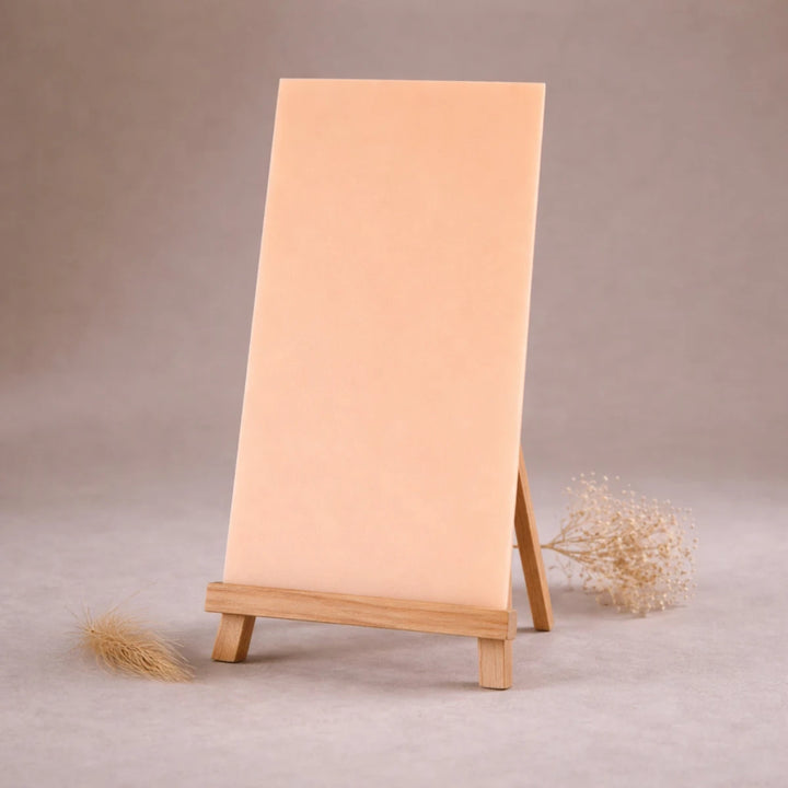 hautfarbene wachsplatte zur kerzengestaltung auf kleiner holzstaffelei vor beigem hintergrund