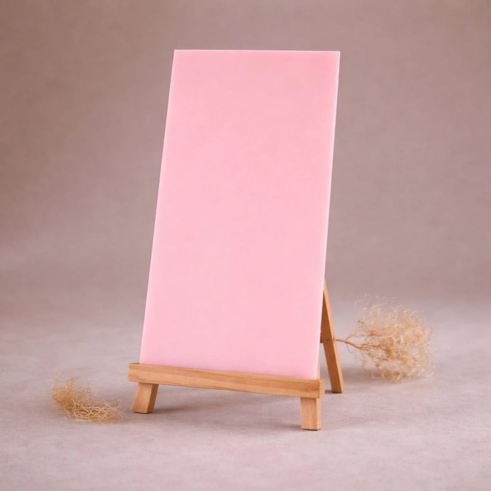 rosafarbene wachsplatte zur kerzengestaltung auf holzstaffelei vor beigem hintergrund