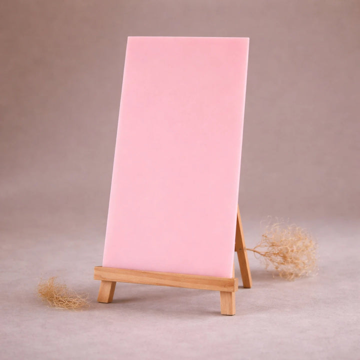 rosafarbene wachsplatte zur kerzengestaltung auf holzstaffelei vor beigem hintergrund
