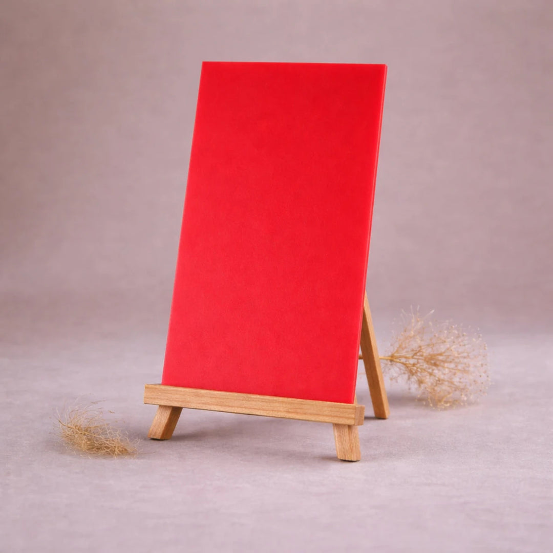 rote wachsplatte zur kerzengestaltung auf kleiner holzstaffelei vor beigem hintergrund