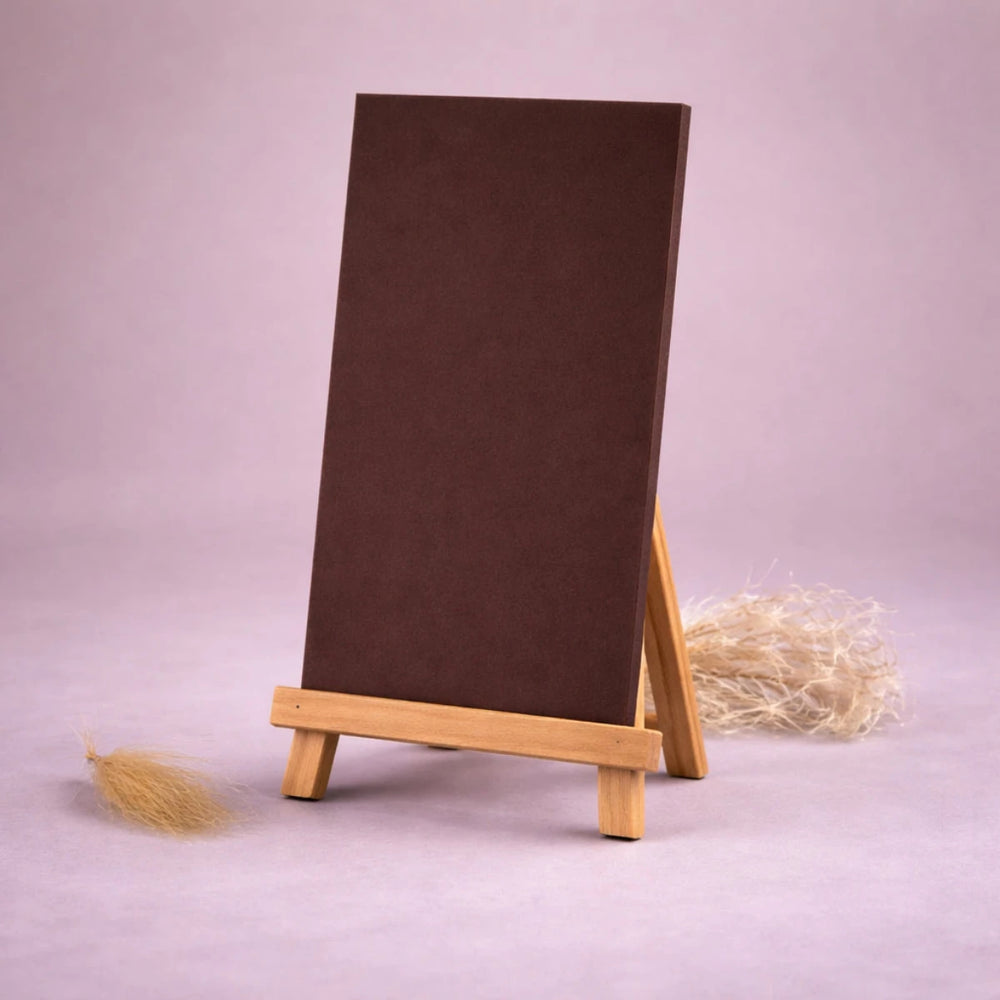 schwarze wachsplatte zur kerzengestaltung auf kleiner holzstaffelei vor neutralem beigem hintergrund