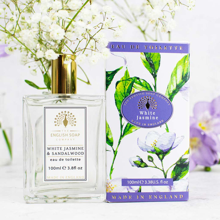 Flasche des Eau de Toilette „White Jasmine & Sandalwood“ mit goldener Verschlusskappe neben der passenden Verpackung im floralen Design.